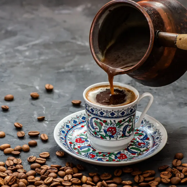 ریختن قهوه ترک از جذوه مسی در فنجان سنتی نقش‌دار