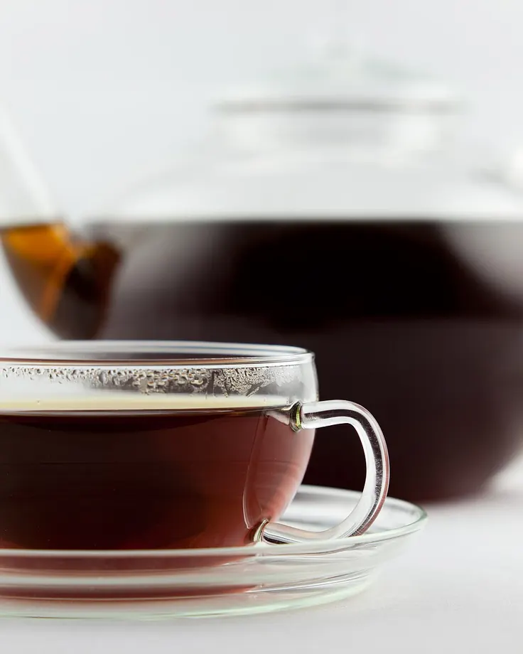 چای سیاه در فنجان شیشه‌ای کنار قوری