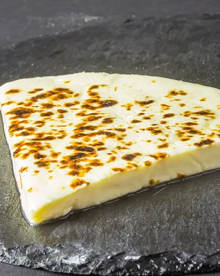 برش پنیر برشته قهوه پنیر روی تخته سنگ گرد