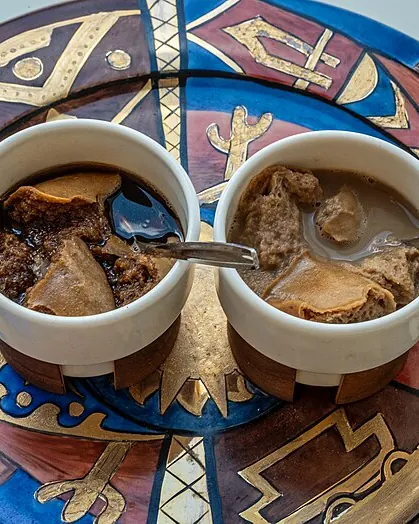 دو فنجان قهوه پنیر با تکههای پنیر شناور روی بشقاب سنتی