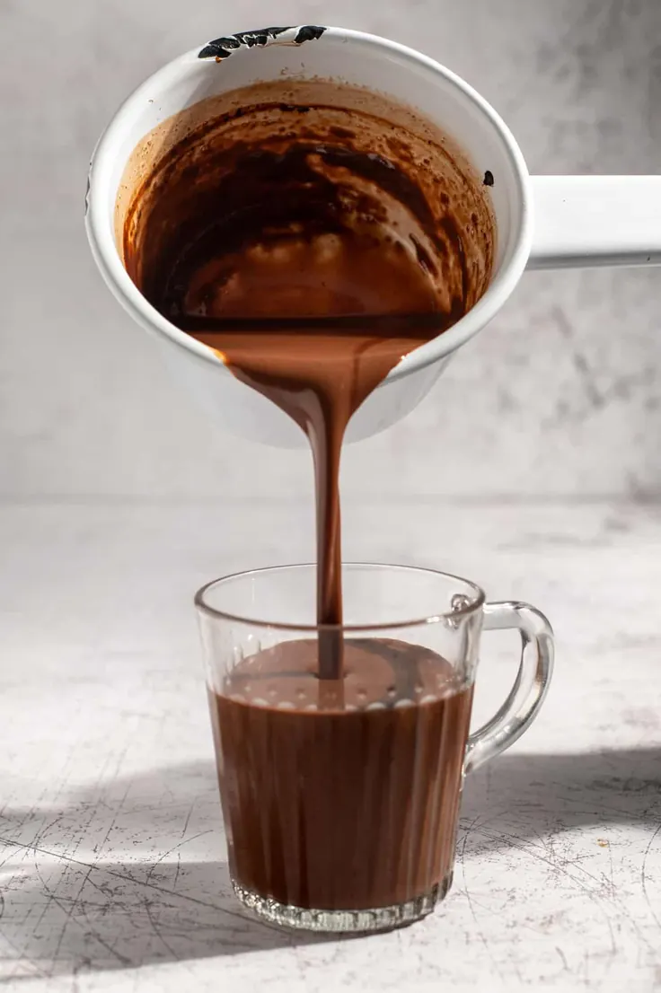 ریختن قهوه شکلاتی غلیظ از کتری در لیوان شیشه‌ای