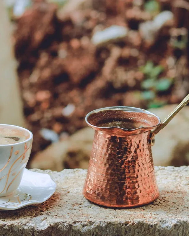 جذوه و فنجان قهوه ترک روی دیوار سنگی؛ قهوه‌ای که پایه فال قهوه است