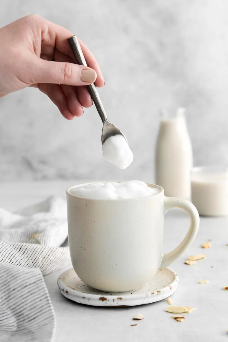 قاشق خامه کف‌شده روی لیوان قهوه خامه‌ای