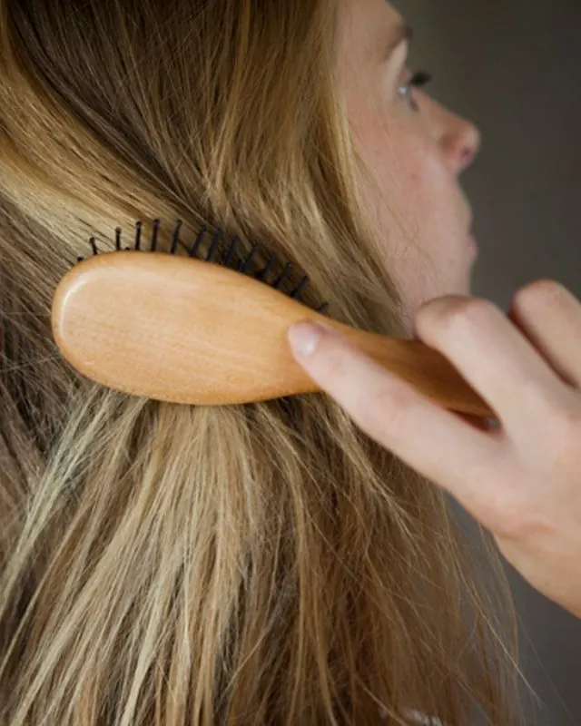 شانه زدن موی بلند با برس چوبی در نمای نزدیک؛ بررسی سلامت مو و ریزش آن